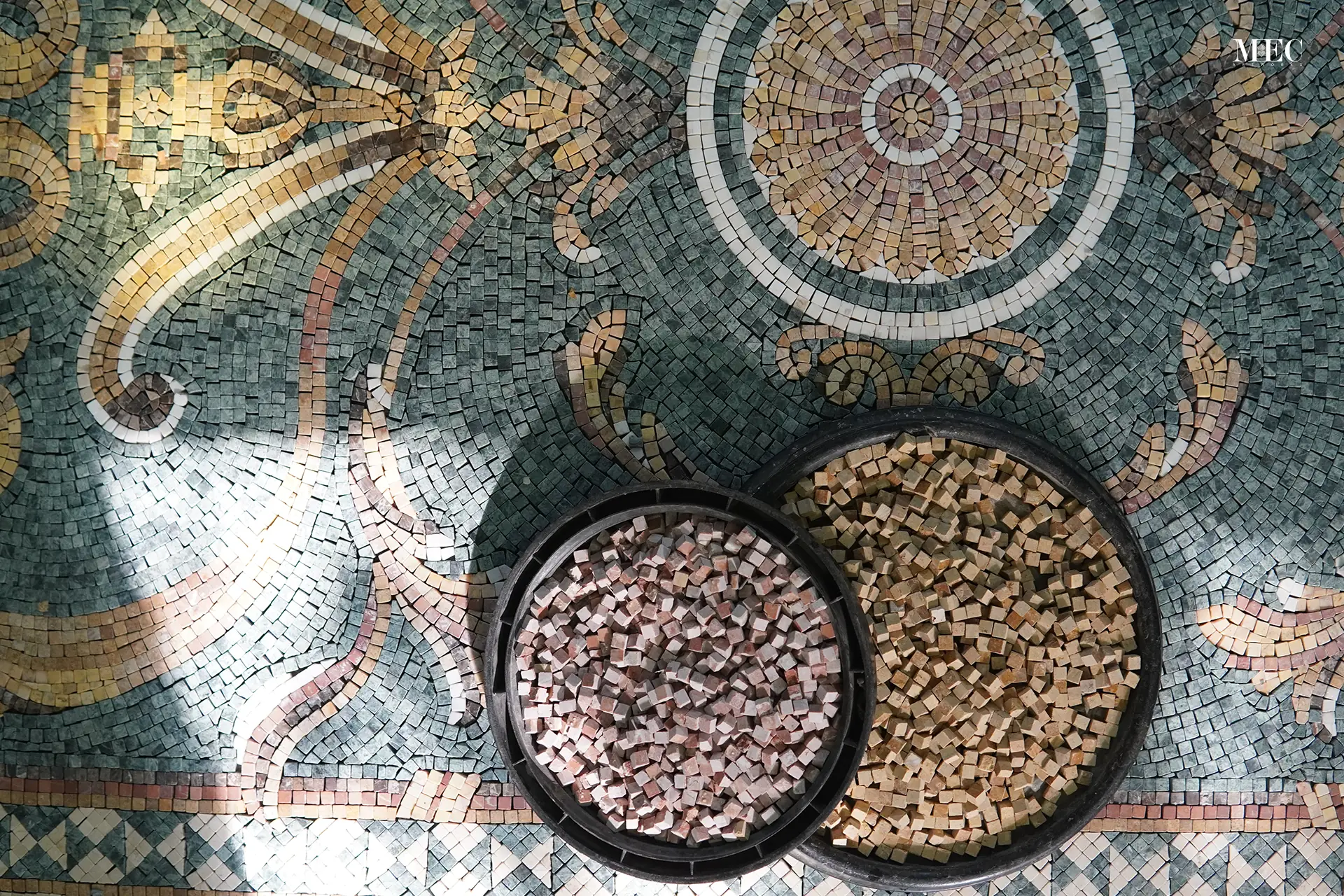 A detailed mosaic floor with two round manhole covers filled with marble mosaics.