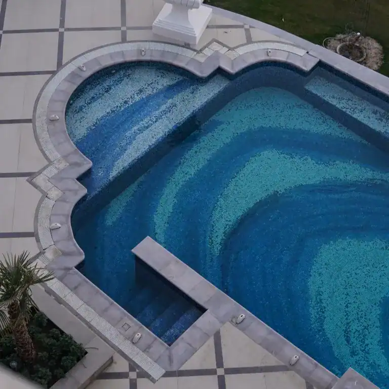 Luxurious swimming pool with intricate blue mosaic tile design, creating a gradient oceanic visual effect.