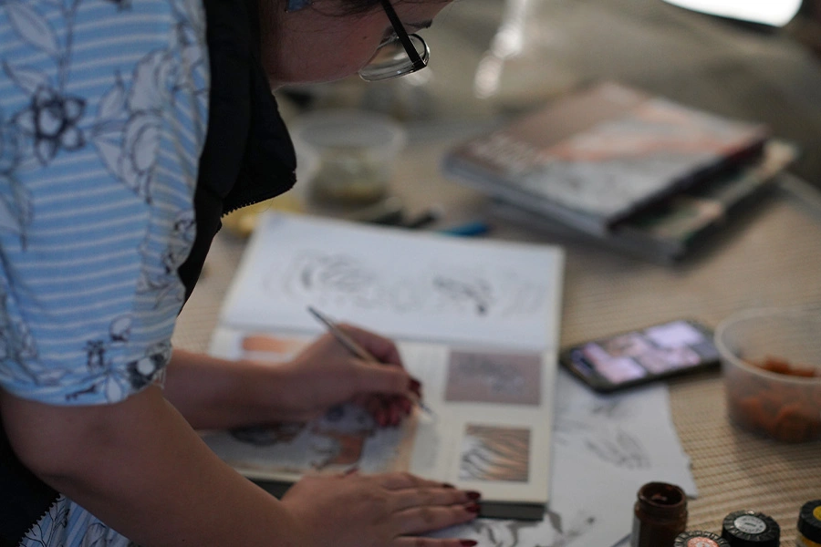 Close-up of artist detailing design concept in sketchbook for professional portfolio or client presentation.