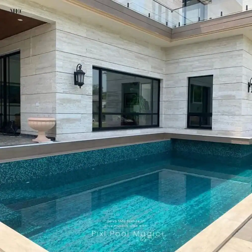Modern private courtyard swimming pool with deep blue mosaic tiles, sleek stone walls, and contemporary home design.