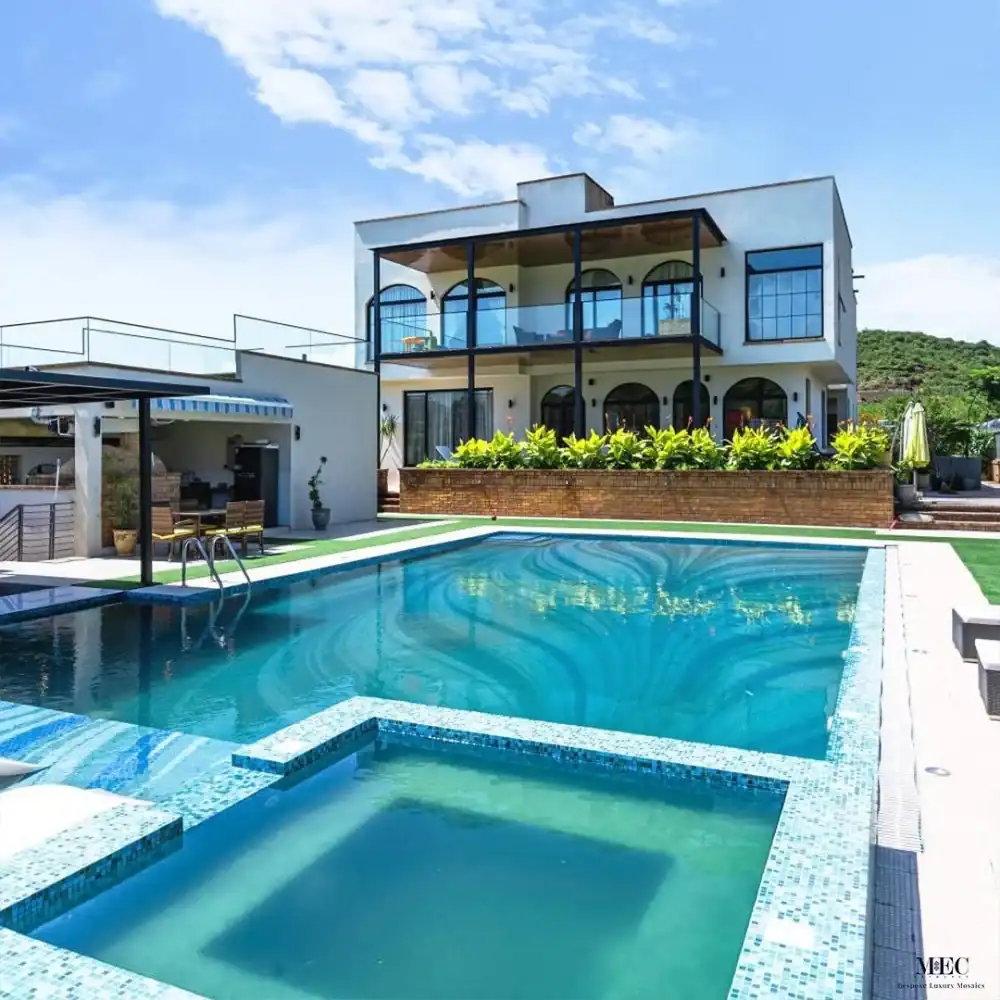 Glass mosaic pool with wave-inspired tile design and built-in jacuzzi corner.