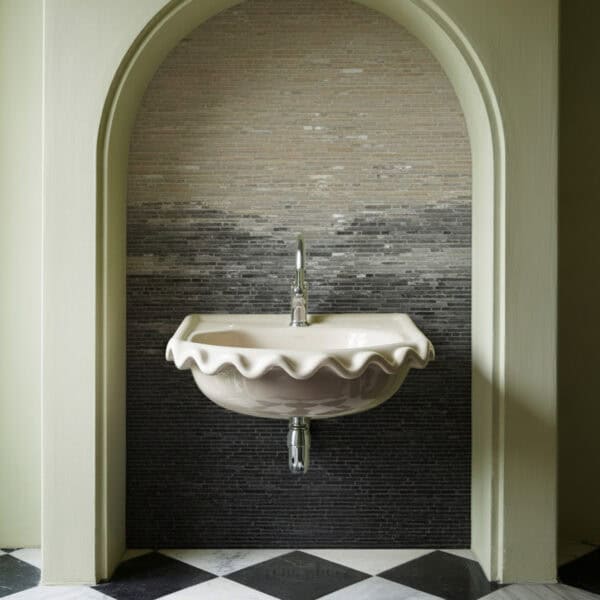 Ash Veil Mosaic Bathroom with a scalloped-edge ceramic sink set in an arched niche, featuring a mosaic wall with a taupe-to-charcoal gradient and black-and-white checkered marble flooring.