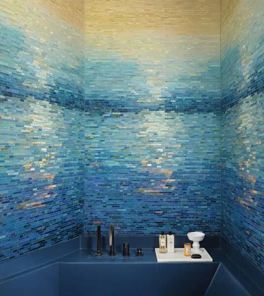 Celeste Horizon Mosaic Luxurious shower with gradient glass mosaic tiles transitioning from golden yellow to deep ocean blue, creating a sunset-over-water effect with matte black fixtures.