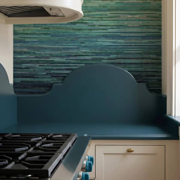 Emerald Tide Glass Mosaic Backsplash Emerald Tide linear glass mosaic used as a modern kitchen backsplash behind a cooktop, featuring layered green mosaic tones.