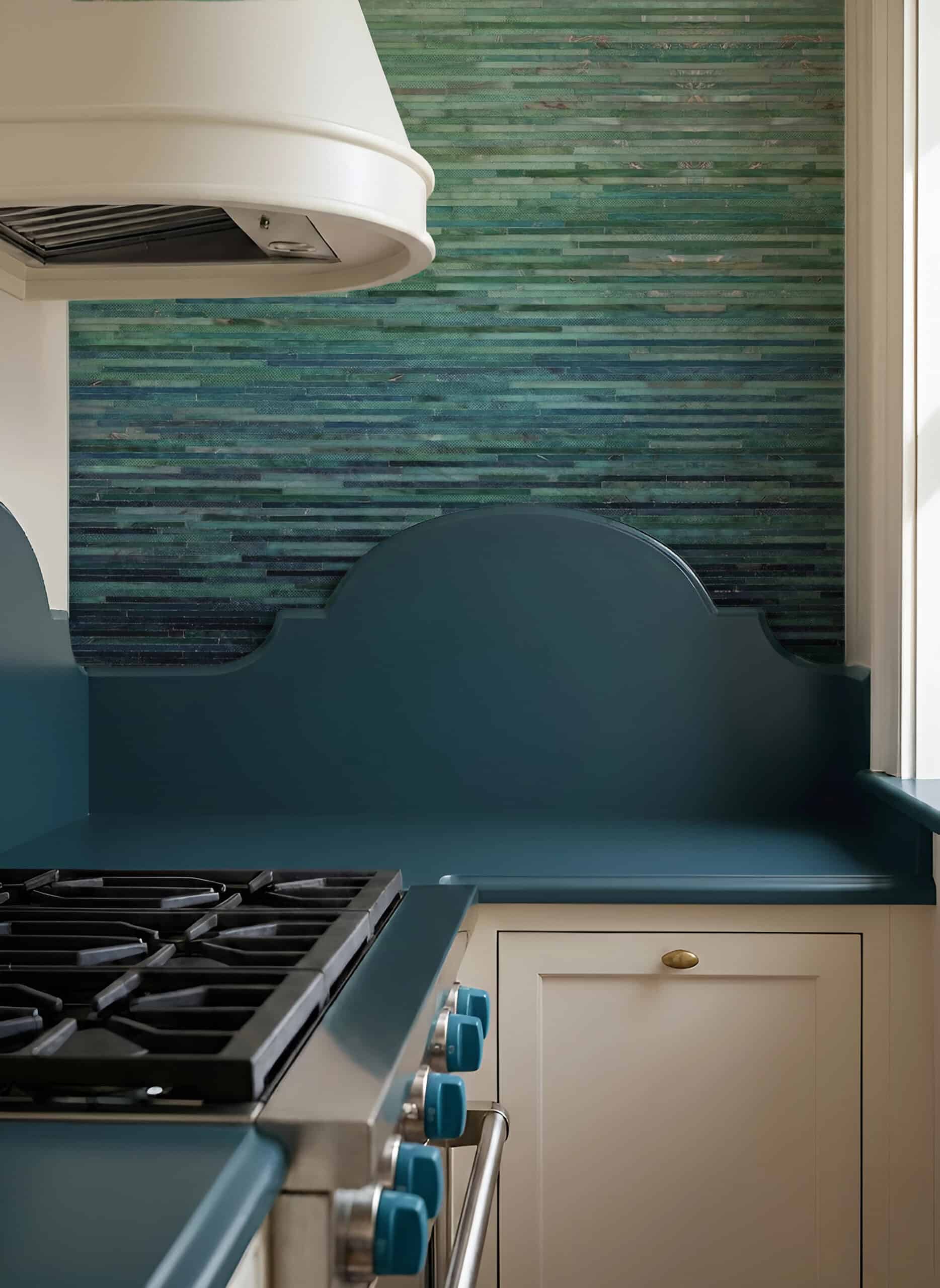 Emerald Tide linear glass mosaic used as a modern kitchen backsplash behind a cooktop, featuring layered green mosaic tones.