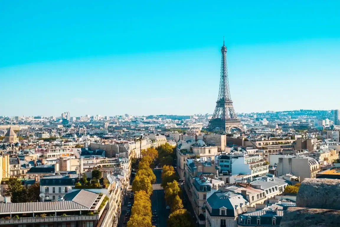 Eiffel Tower rises over Paris skyline on a clear day with classic French architecture below.